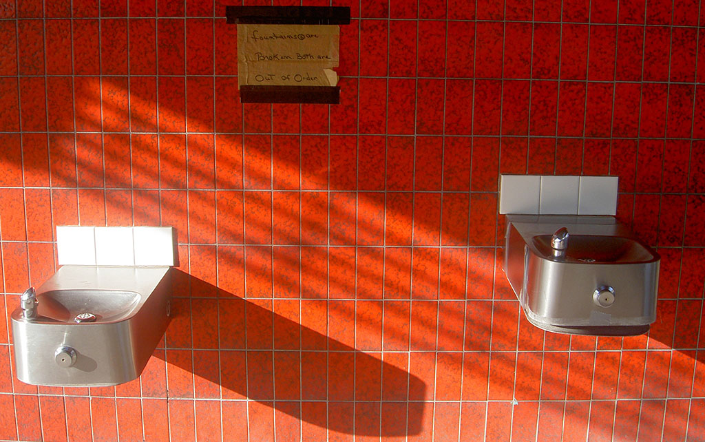 Broken drinking fountains on a red tiled wall