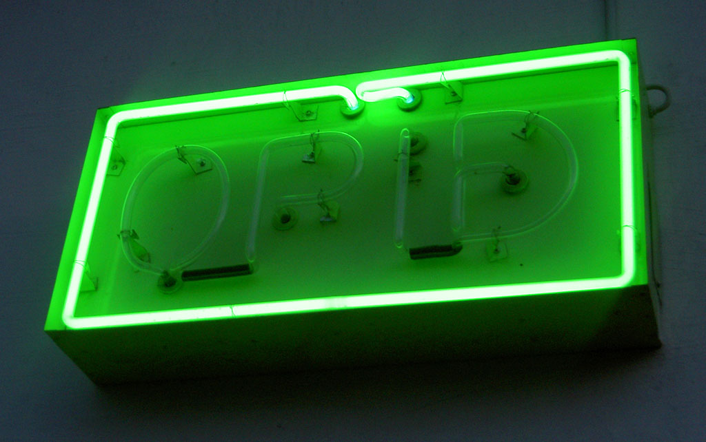 Green neon shop 'open' sign that reads 'Opid' in Icelandic