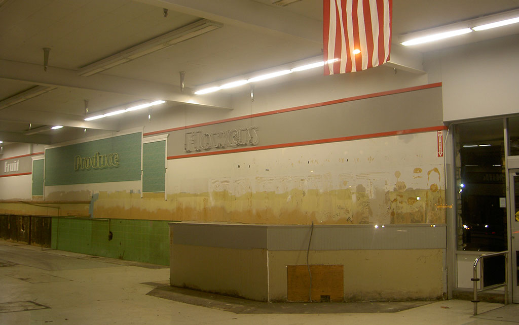Abandoned supermarket in Monterey with American flag and signs for Produce and Flowers